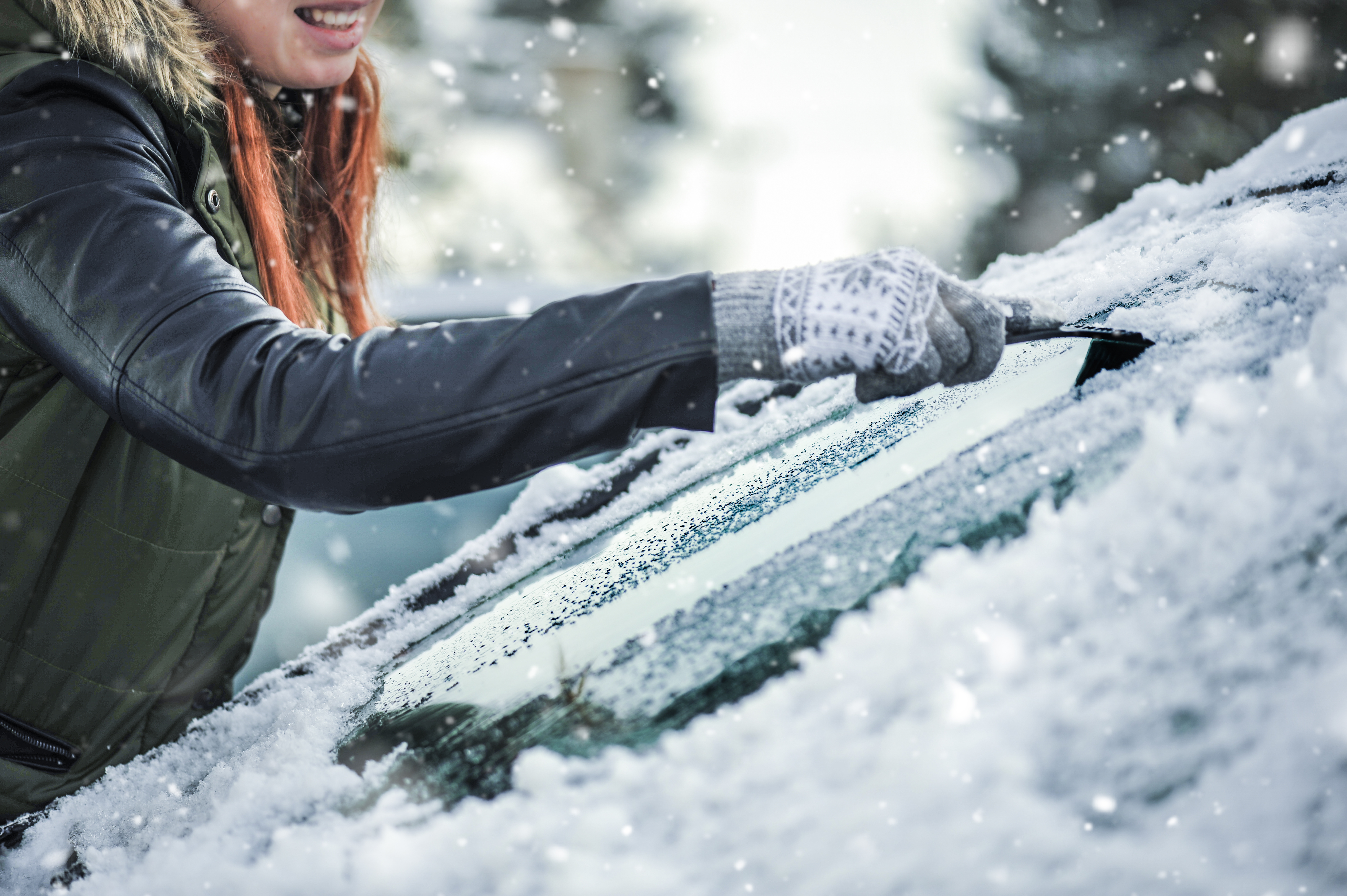 Removing snow from car windshield. Clean car window in winter from snow